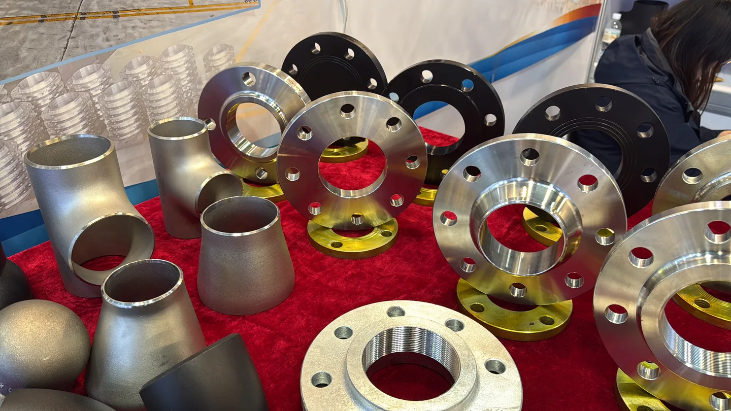 Metal flanges, elbows, tees and reducers arranged on a red-covered display table