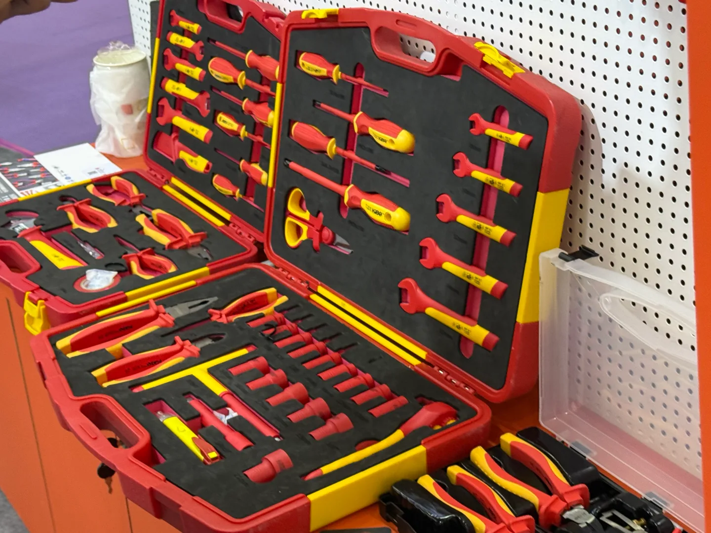 Open red carrying cases with red and yellow hand tools arranged in fitted inserts