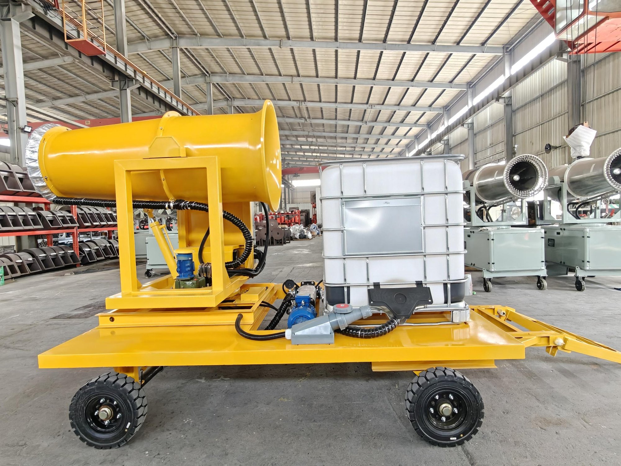 Yellow mobile fog cannon unit with a fan assembly and water tank inside a workshop
